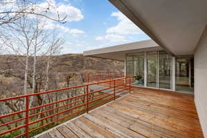 Expansive outdoor deck featuring wood-finish flooring and a red metal railing