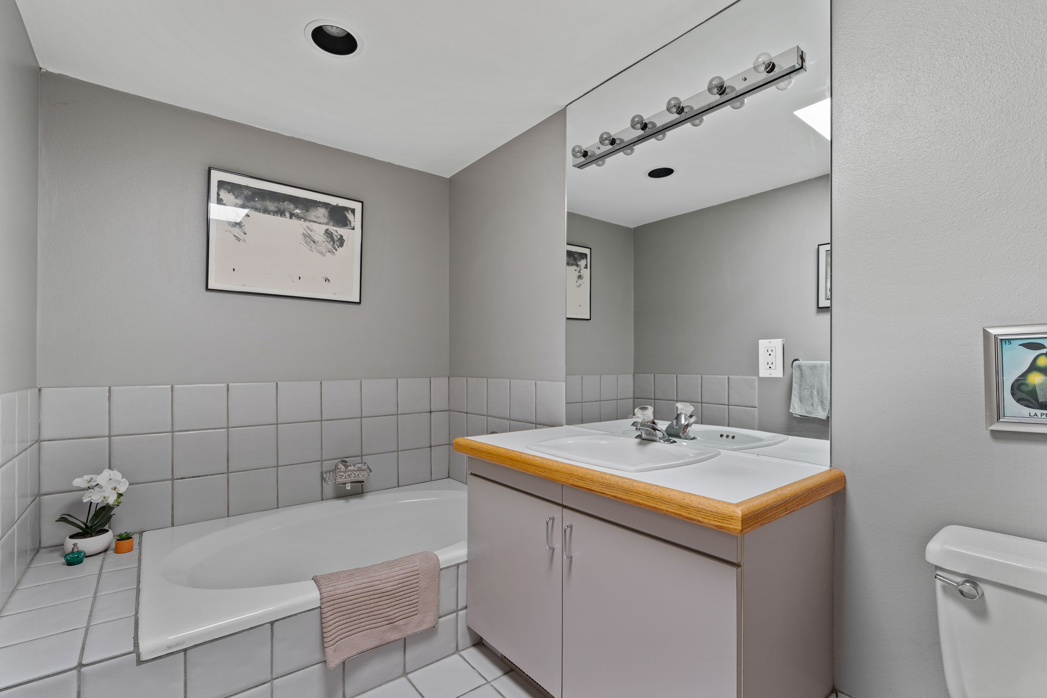 Bathroom featuring a built-in bathtub, a vanity with a laminate countertop, and an integrated sink