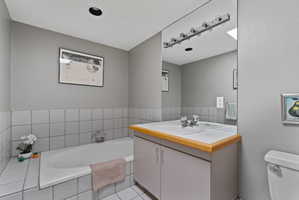 Bathroom featuring a built-in bathtub, a vanity with a laminate countertop, and an integrated sink