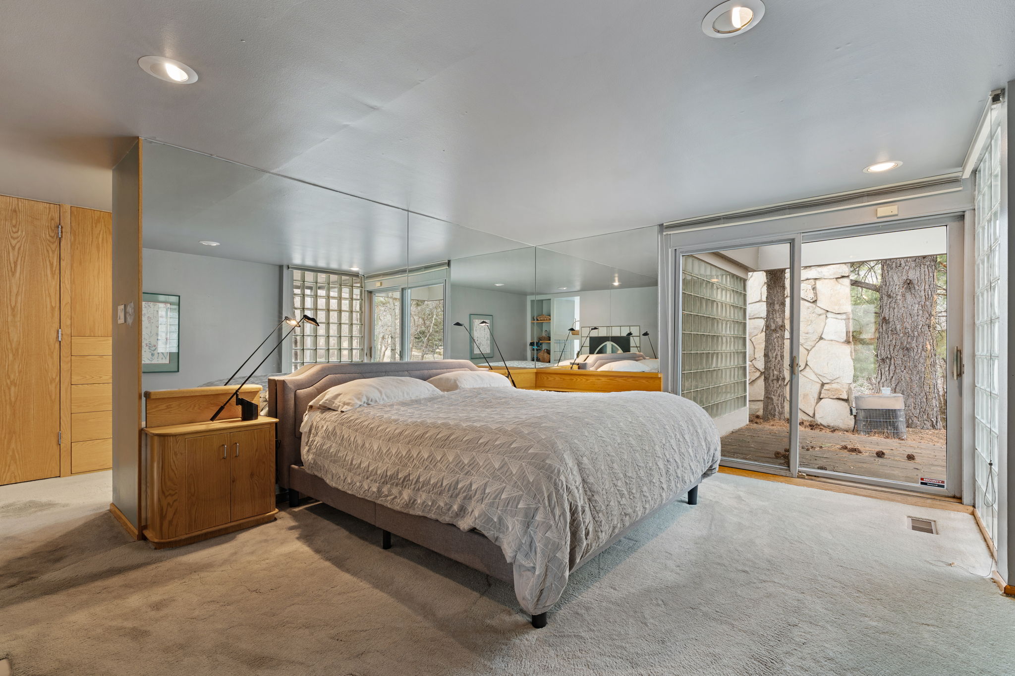 Carpeted room featuring a large sliding glass door, recessed lighting, mirrored wall panels, and built-in wood-finish cabinetry