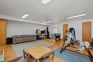 Spacious room featuring wood-finish flooring, white walls, and multiple flush-mount ceiling light fixtures
