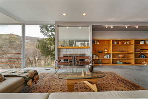 Living area featuring expansive windows, built-in shelving, recessed lighting, and a tiled fireplace surround with a wood mantel