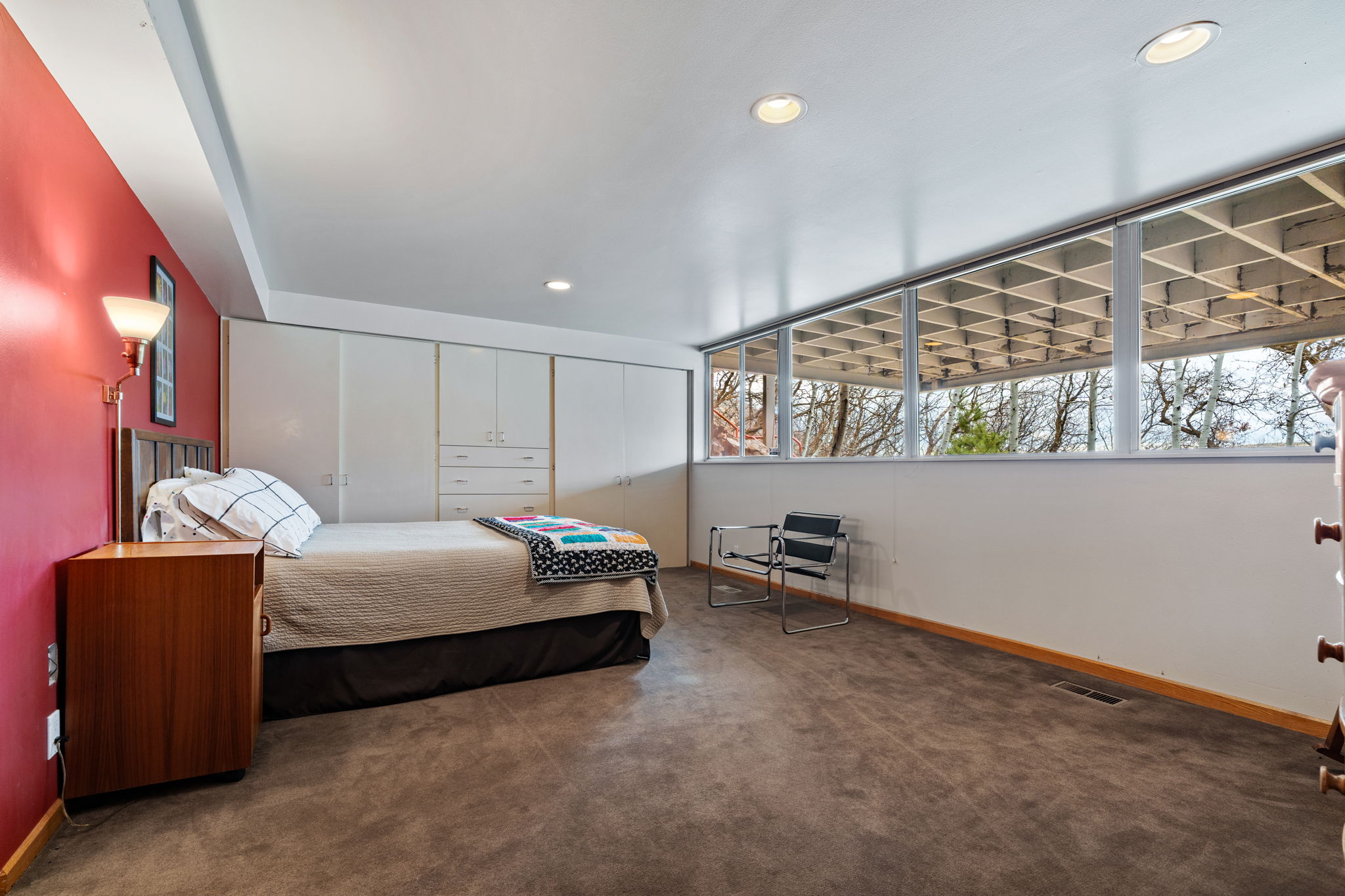 Room featuring a built-in wall of cabinetry, a floor-to-ceiling window wall with exterior grid detailing, recessed ceiling lighting, and a red accent wall