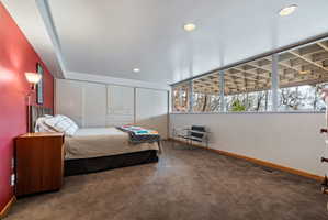 Room featuring a built-in wall of cabinetry, a floor-to-ceiling window wall with exterior grid detailing, recessed ceiling lighting, and a red accent wall