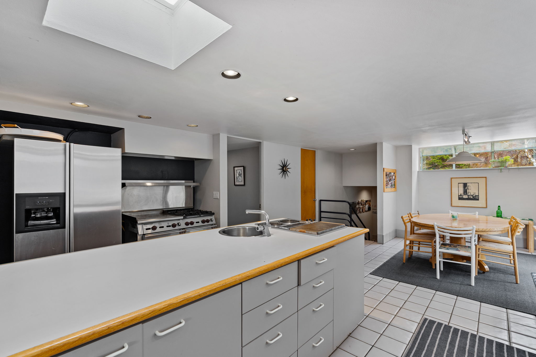 Kitchen featuring a central island with integrated sink, stainless steel appliances, recessed lighting, and a skylight