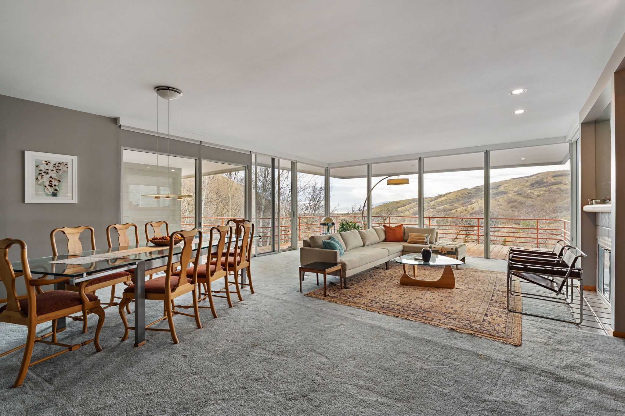 Open-concept living area with extensive floor-to-ceiling windows, gray wall paint, recessed lighting, and light gray carpeting
