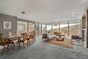 Open-concept living area with extensive floor-to-ceiling windows, gray wall paint, recessed lighting, and light gray carpeting