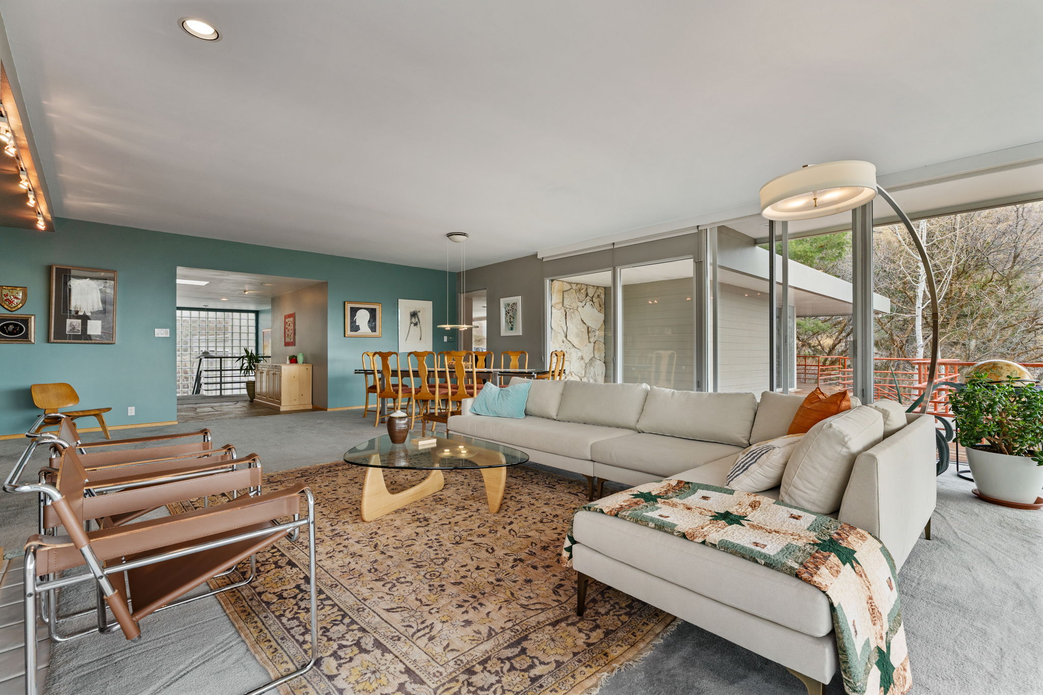Open-concept living area with extensive floor-to-ceiling windows, recessed lighting, and a stone accent wall