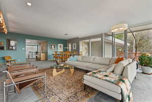Open-concept living area with extensive floor-to-ceiling windows, recessed lighting, and a stone accent wall