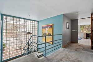 Staircase with glass block wall, metal railing, and carpeted treads