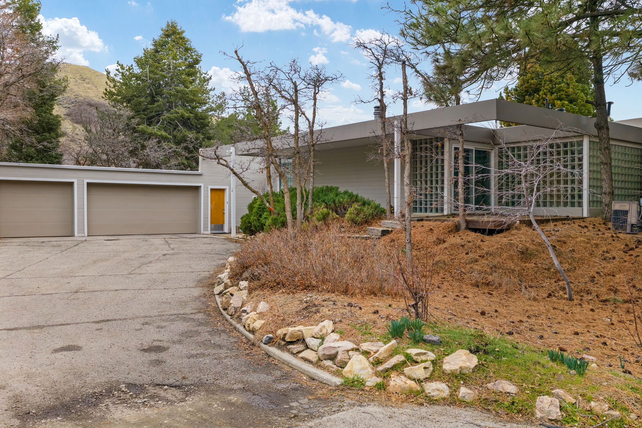 Contemporary architectural style with extensive glass block window walls, a two-car garage, and a bright yellow entry door