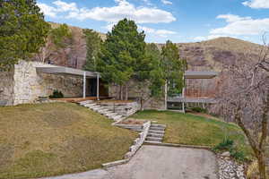 Stone-clad exterior featuring a covered entry, wood decking, and tiered landscaping