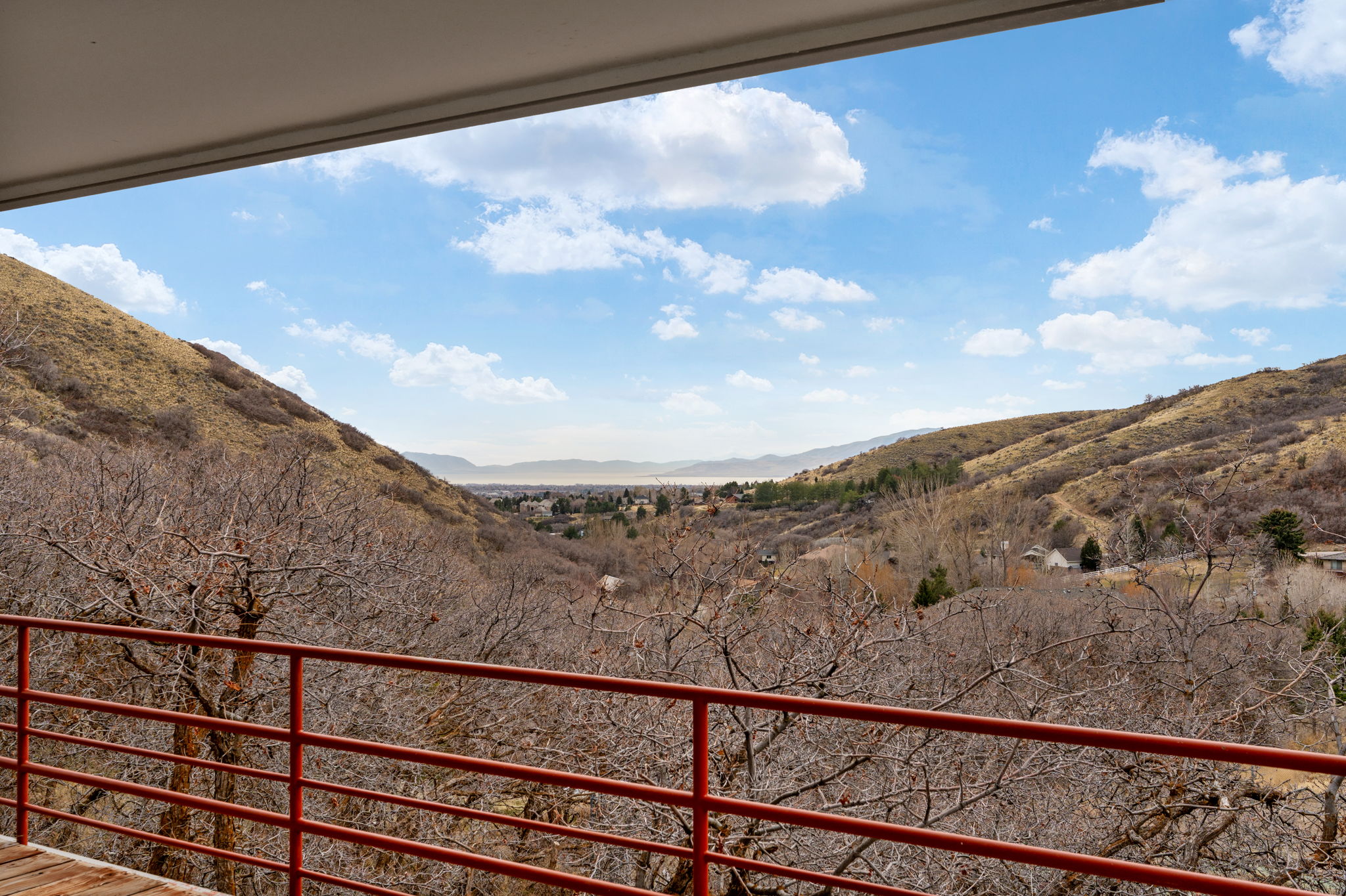 Outdoor balcony with red metal railing, offering expansive mountain and valley scenery