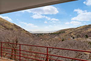 Outdoor balcony with red metal railing, offering expansive mountain and valley scenery