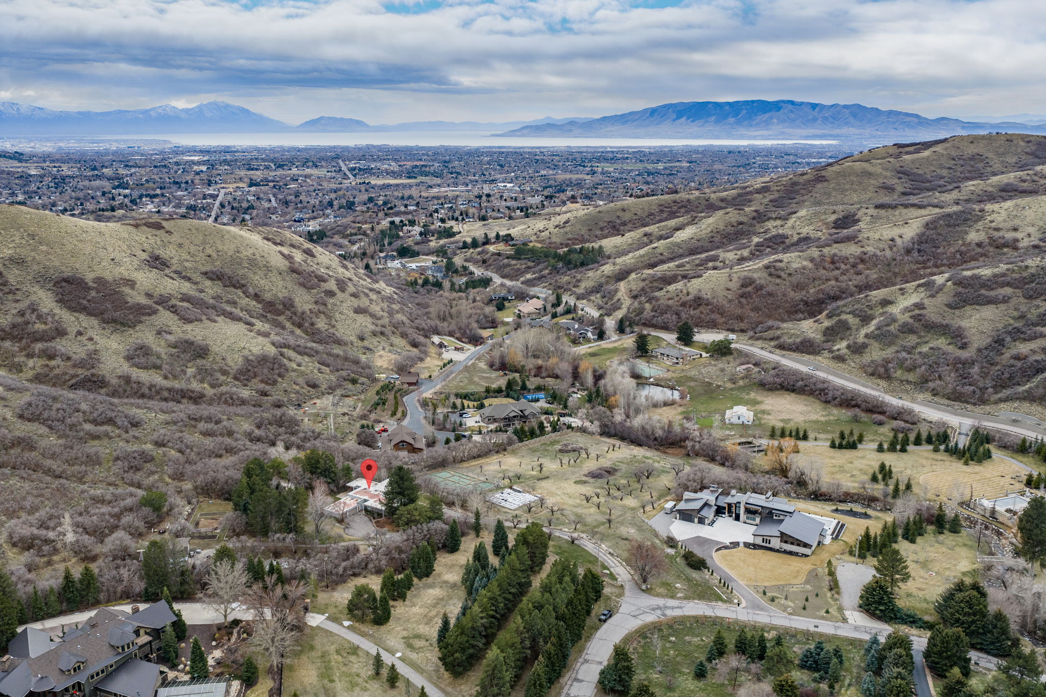 Elevated property set against a backdrop of rolling hills and distant mountains, featuring a diverse landscape with mature trees and open terrain