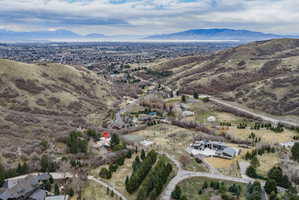 Elevated property set against a backdrop of rolling hills and distant mountains, featuring a diverse landscape with mature trees and open terrain