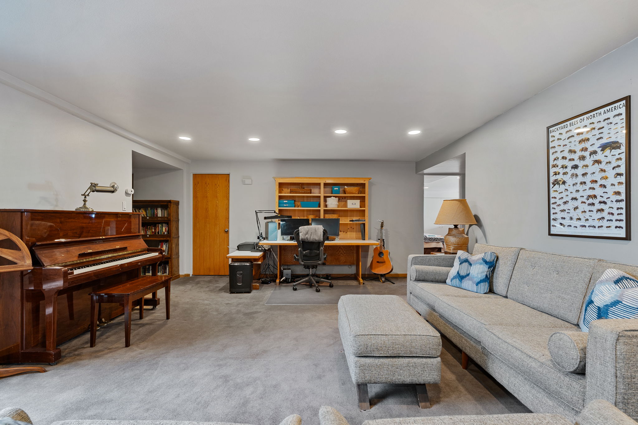 Spacious room featuring light gray walls, recessed lighting, and gray carpeting