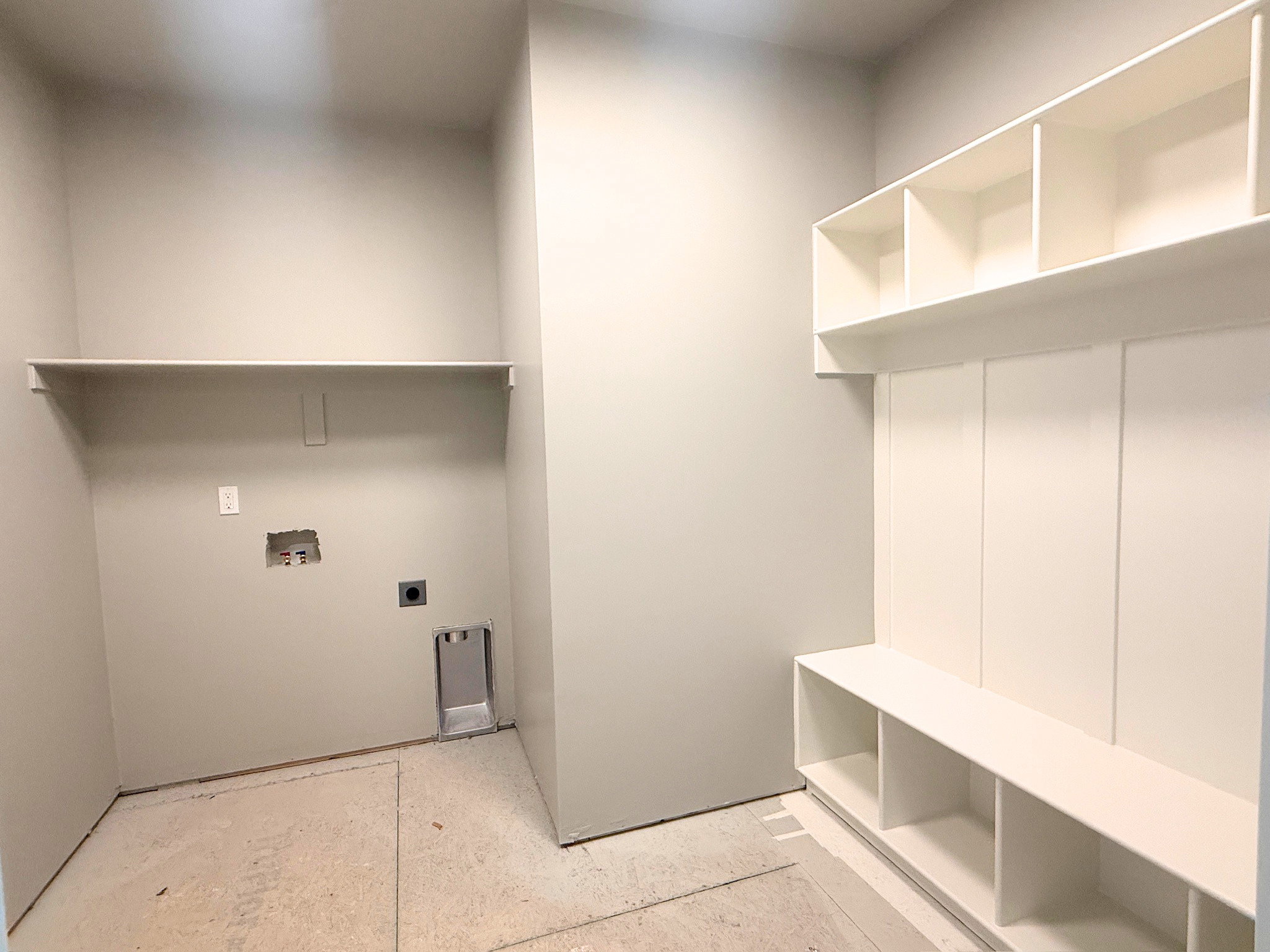 Laundry area featuring a utility shelf and built-in storage bench with overhead cubbies