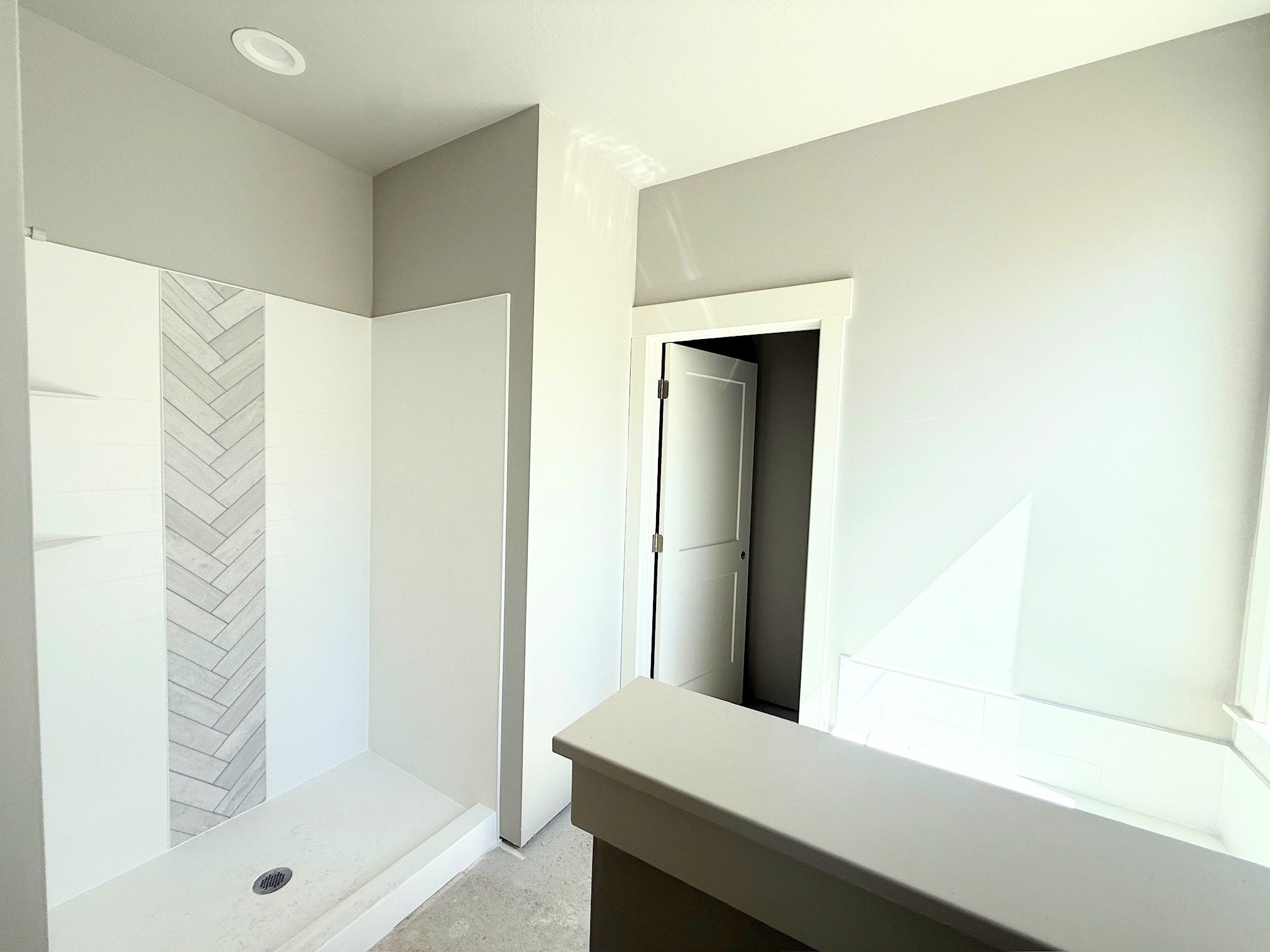 White shower enclosure featuring a herringbone-patterned tile accent