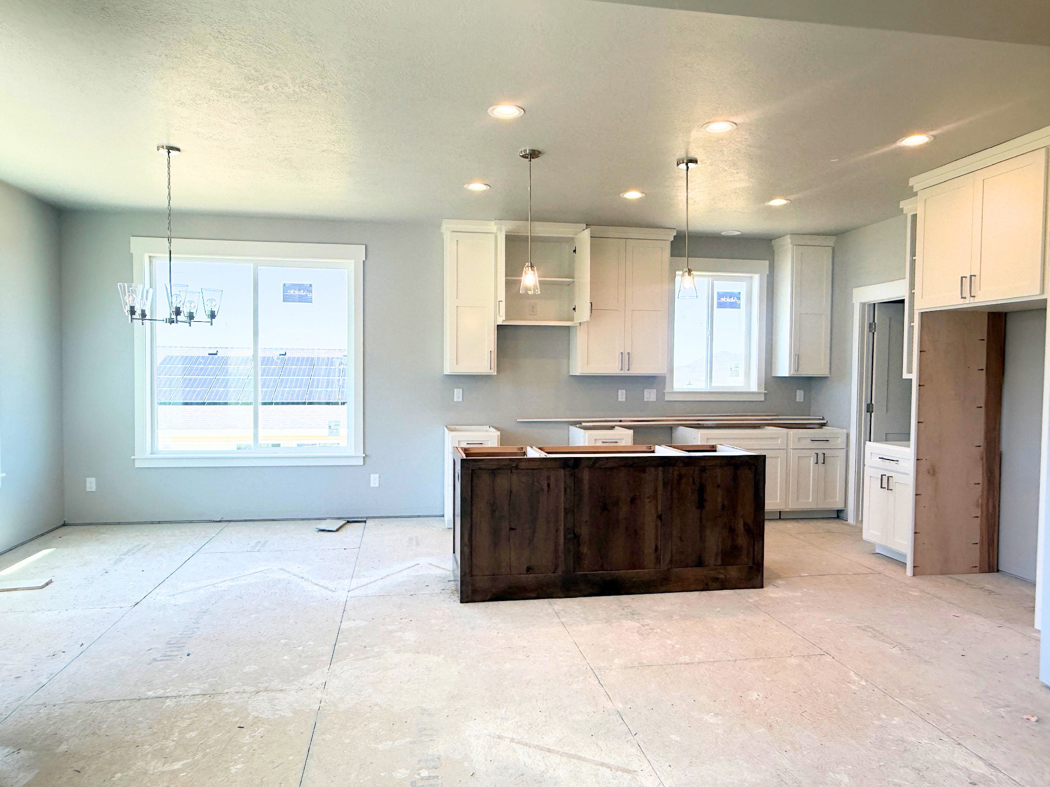 Spacious open-concept kitchen and dining area featuring a dark wood-finish island, white shaker cabinetry, and multiple windows