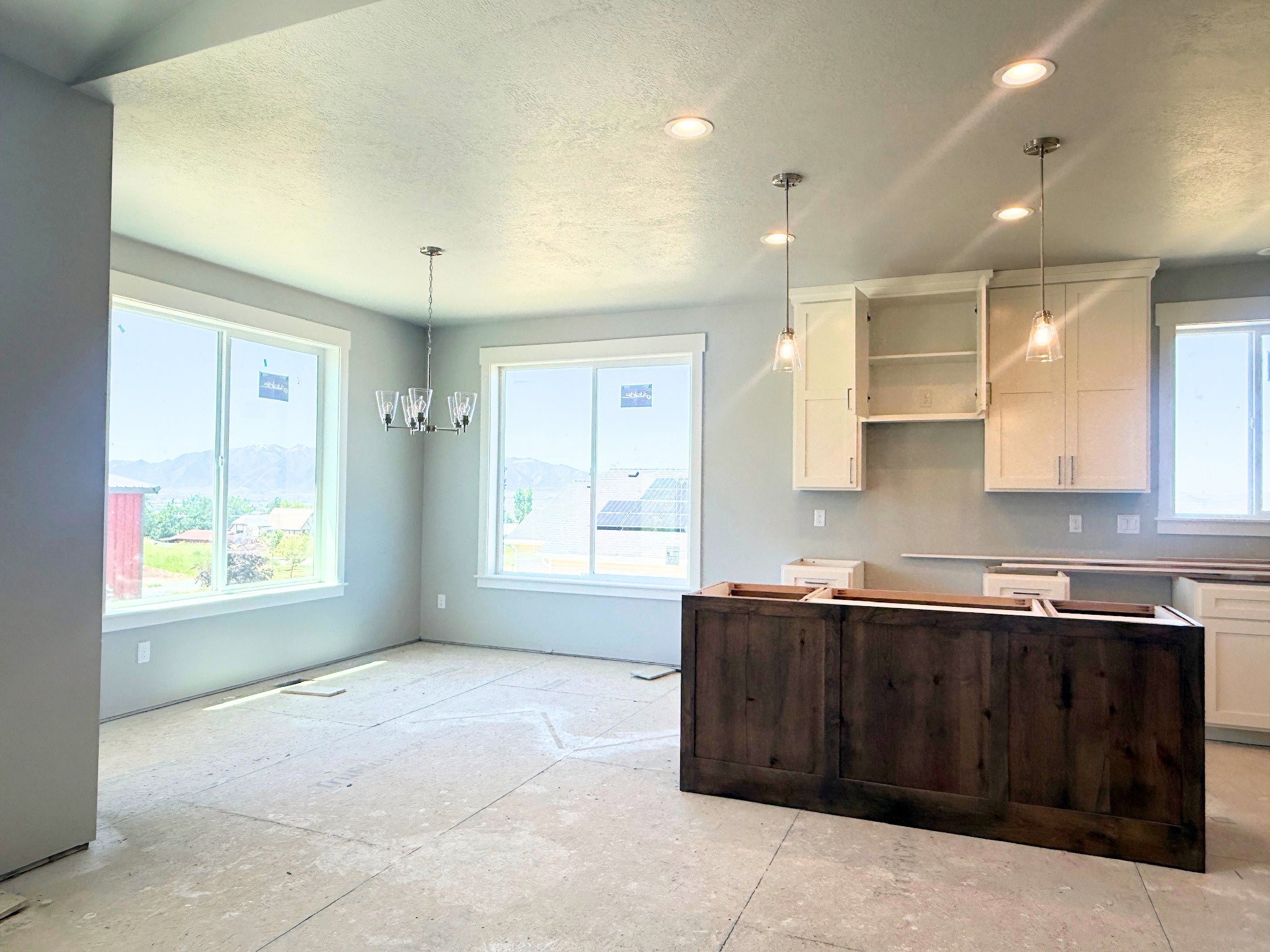 Spacious interior featuring a large kitchen island with dark wood-finish cabinetry, white upper cabinetry, and ample natural light from multiple windows