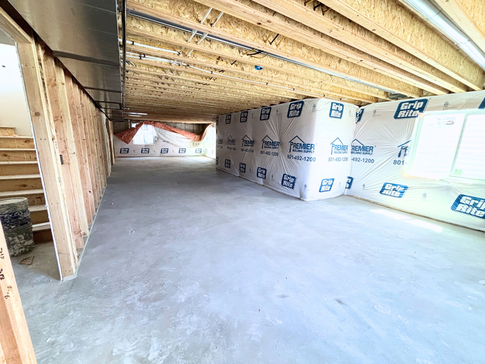 Unfinished basement with concrete flooring, exposed wood joists, and framed walls