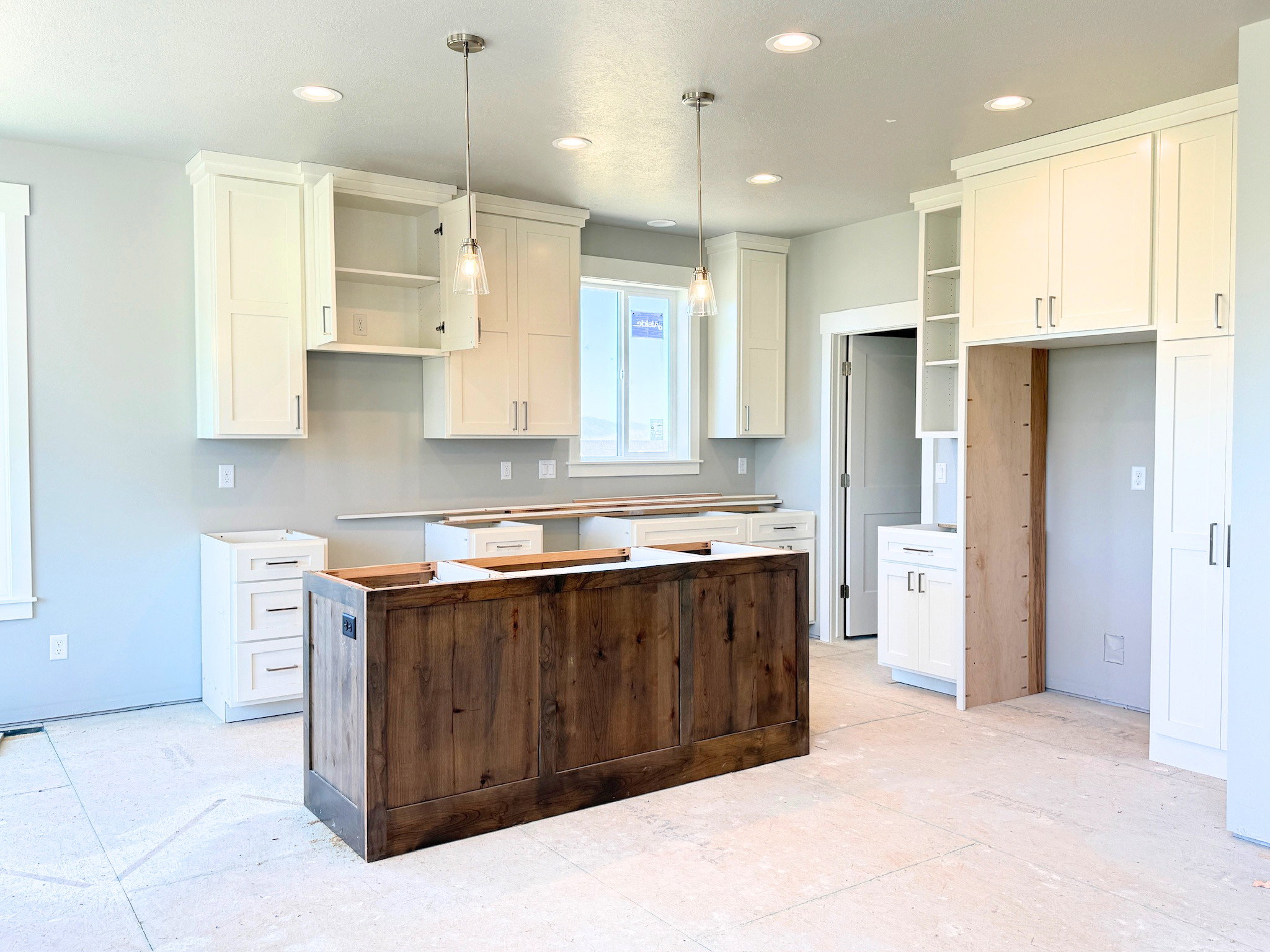 Kitchen featuring a substantial wood-finish island, white shaker cabinetry, recessed lighting, and pendant lights