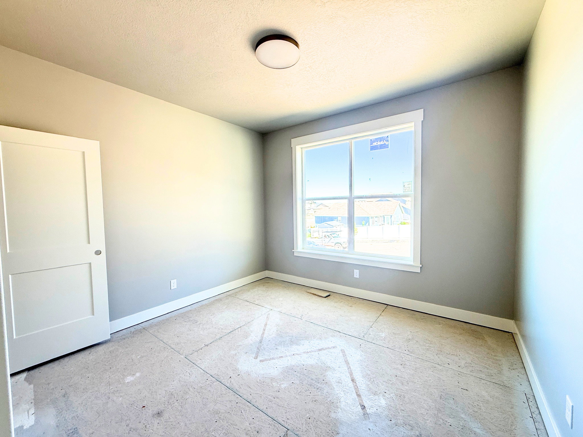 Bright interior space featuring a large window with white trim, light gray painted walls, and a modern flush-mount ceiling light