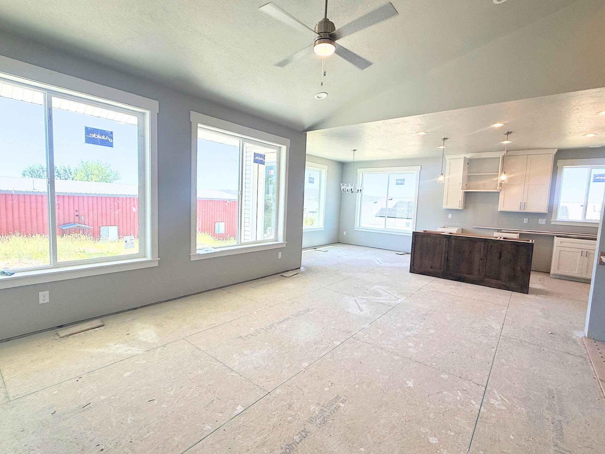Spacious open-concept living area featuring multiple large windows, a ceiling fan with integrated lighting, and recessed lighting