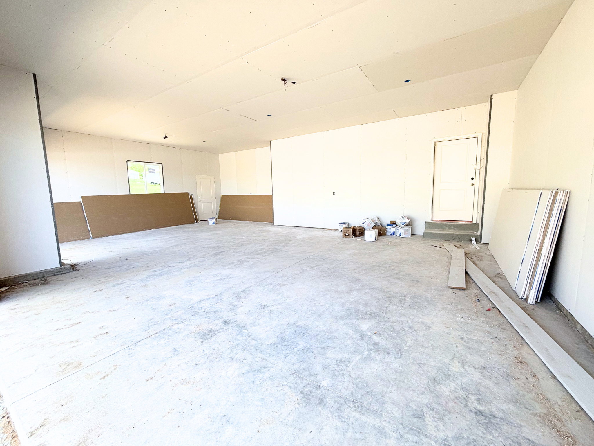Spacious garage with unfinished walls, concrete flooring, and an entry door