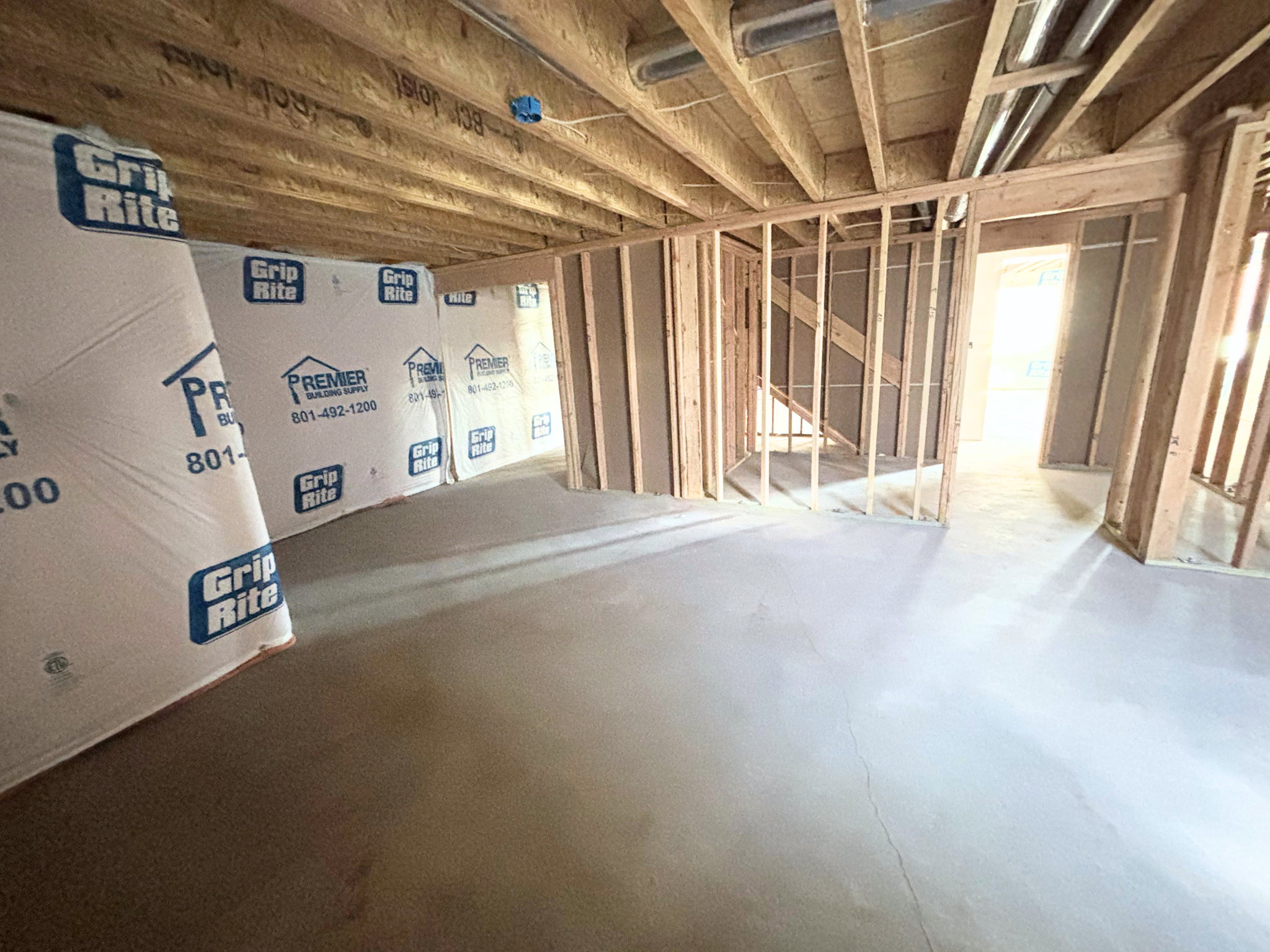 Unfinished interior space featuring exposed wood framing, concrete flooring, and visible ceiling joists