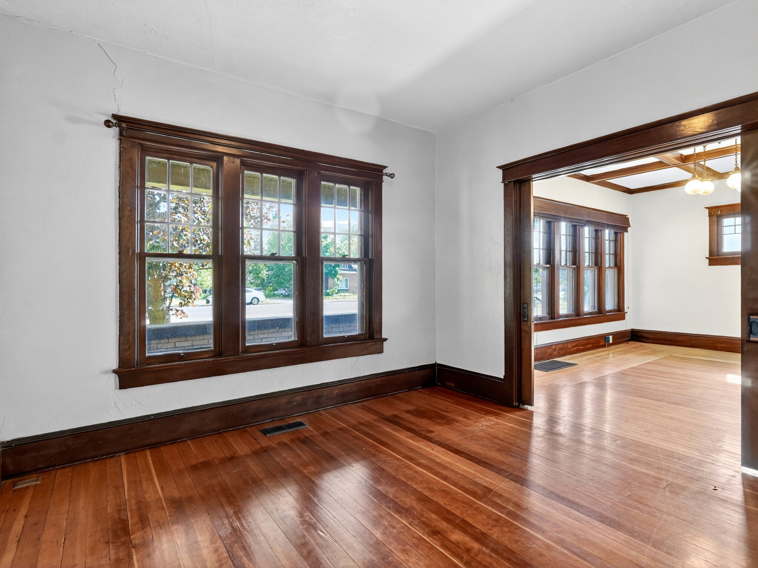 Hardwood flooring throughout, featuring a wide trim baseboard and window casing in a deep wood finish