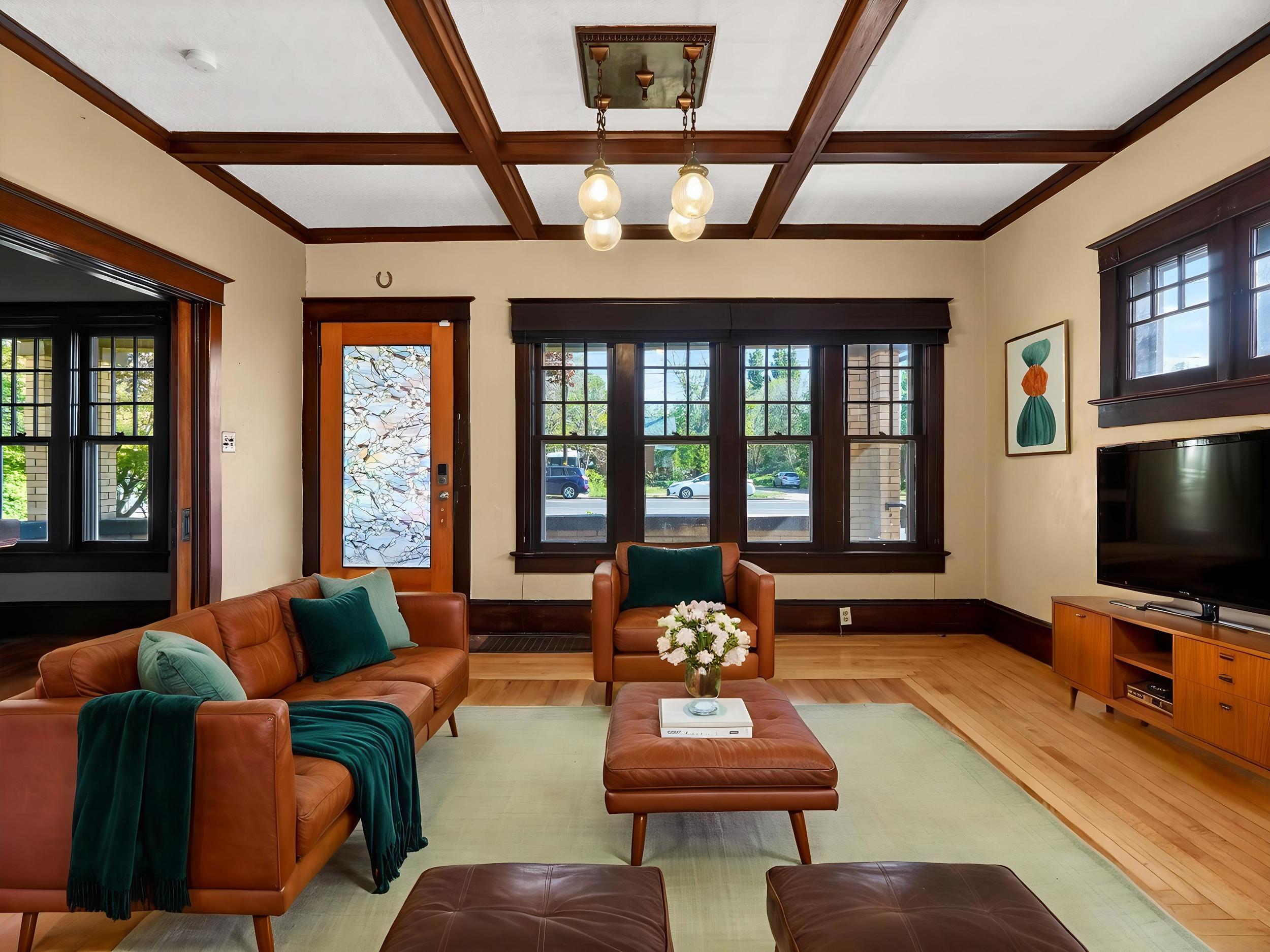Living space featuring coffered ceilings, clear wood-finish flooring, and dark wood-trimmed windows