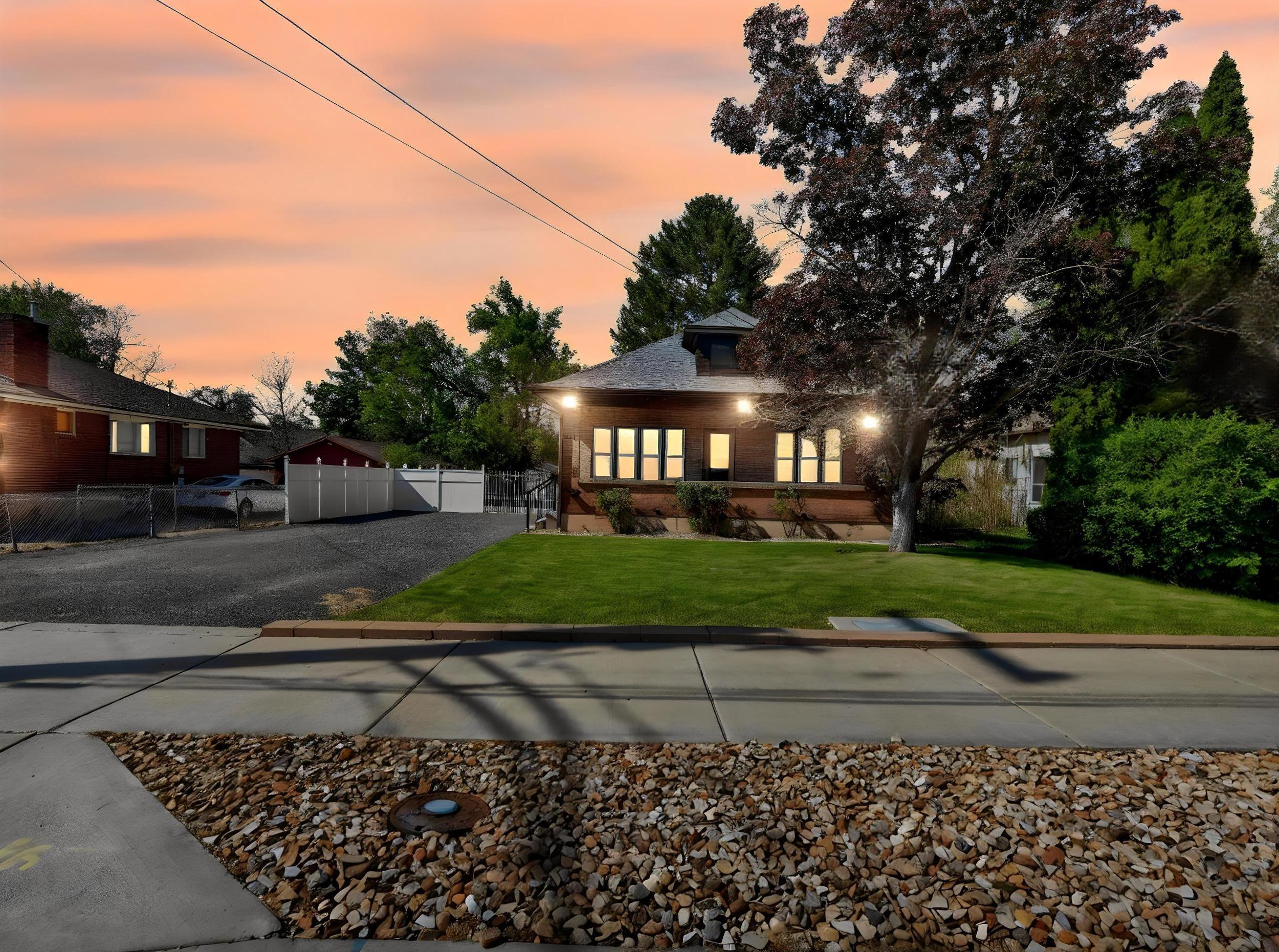 Brick facade residence with a well-maintained front lawn, mature tree, and multiple windows