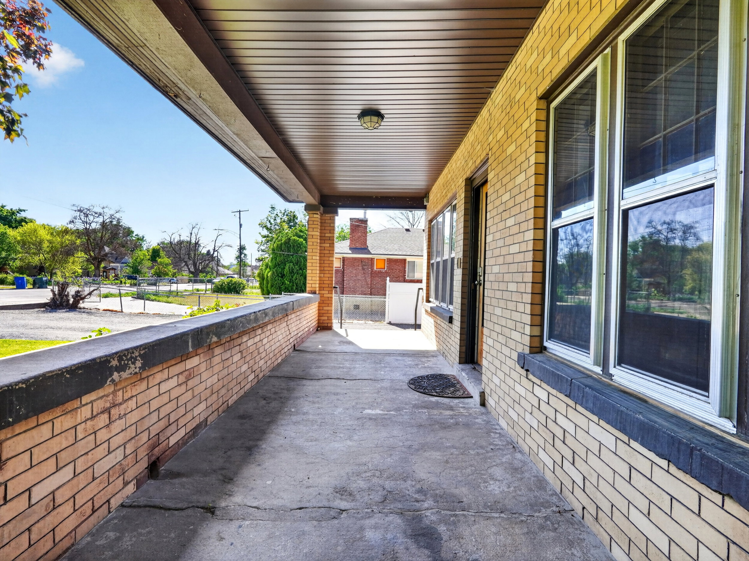 Covered porch featuring a concrete floor, light brick facade, and a dark soffit ceiling