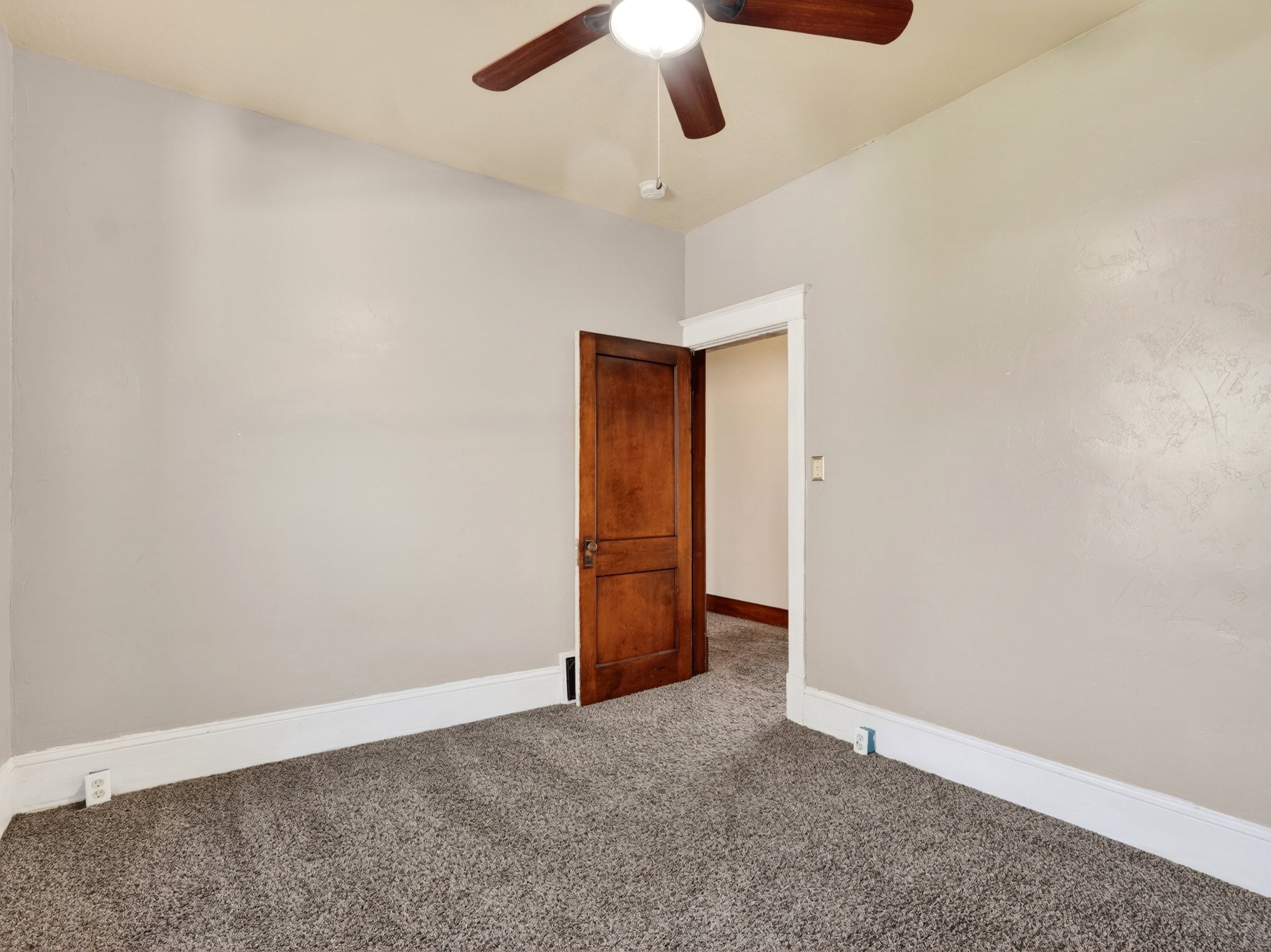 Carpeted room with a ceiling fan light fixture