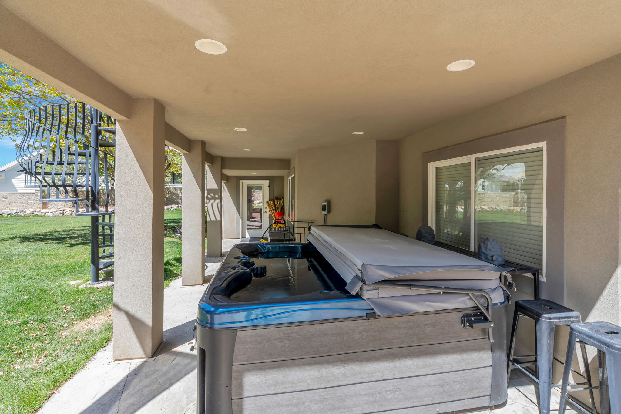 Covered patio featuring a built-in hot tub, recessed lighting, and a spiral staircase providing exterior access