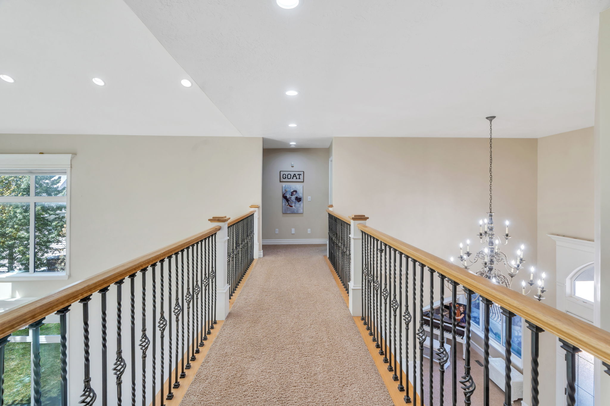 Carpeted hallway with wood and wrought iron railings overlooking a lower level