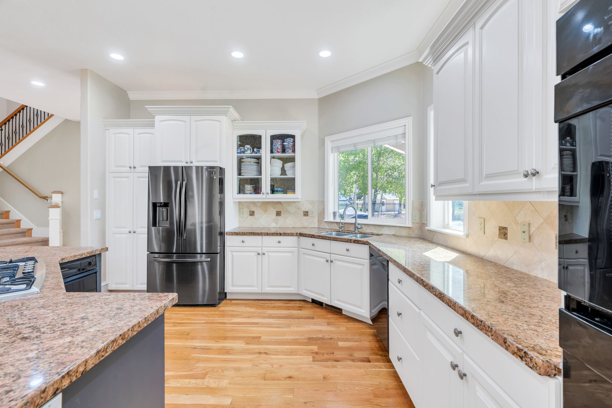Kitchen featuring light wood-finish flooring, white cabinetry, granite countertops, and stainless steel appliances