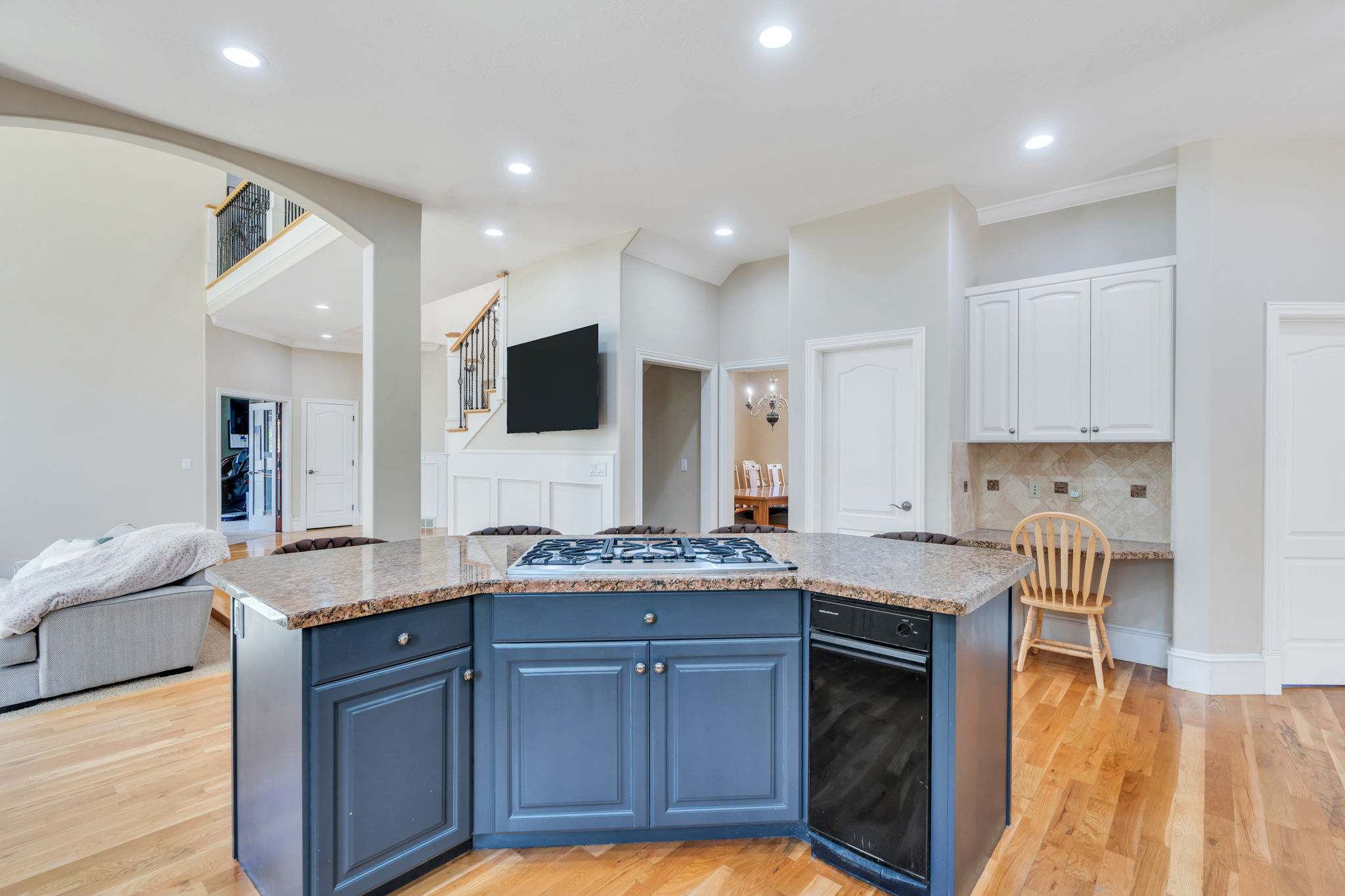 Central kitchen island with a built-in cooktop and dishwasher, granite countertops, and blue cabinetry