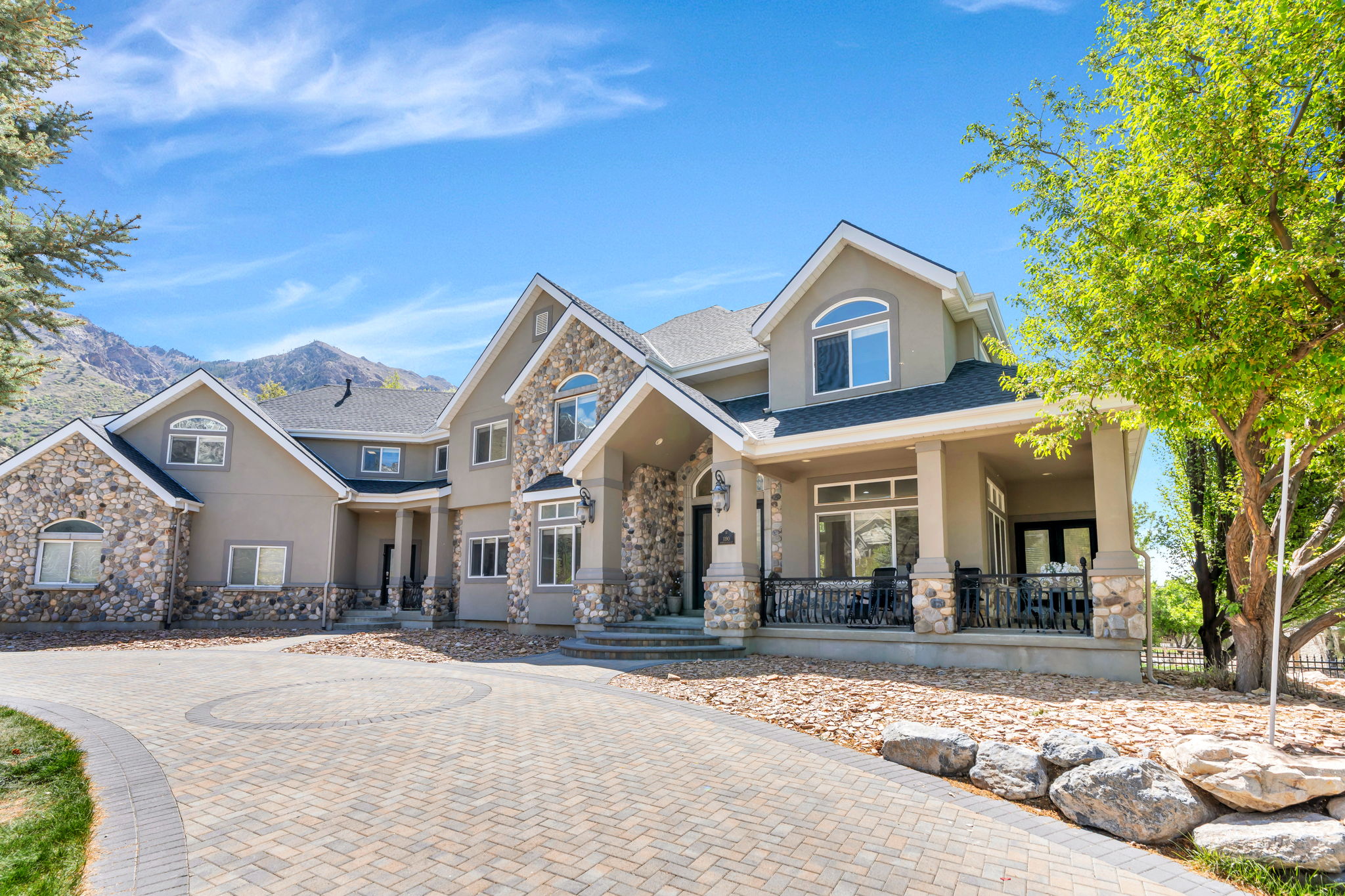 Stucco and stone exterior featuring multiple gables and dormers