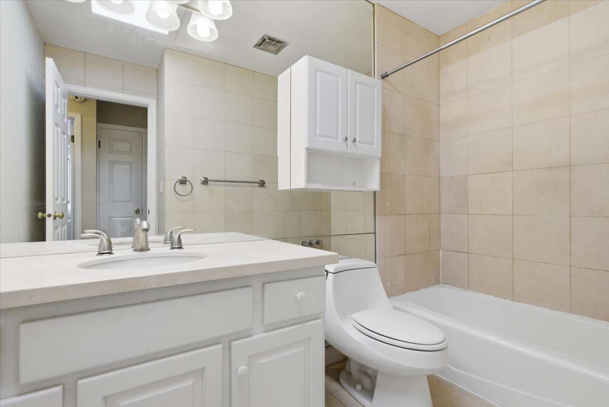 Bathroom featuring a white vanity with an undermount sink, a light-toned countertop, and a full-width mirror