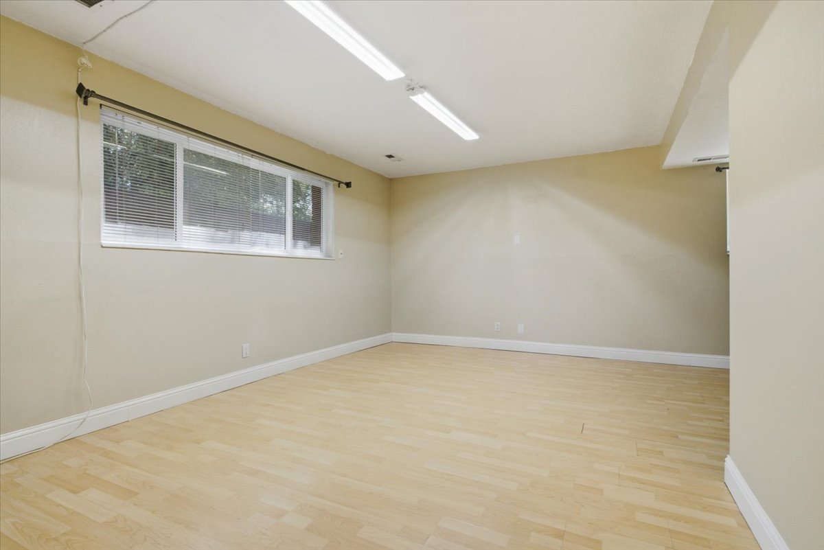 Spacious room featuring light wood-finish flooring, neutral wall tones, and white baseboards