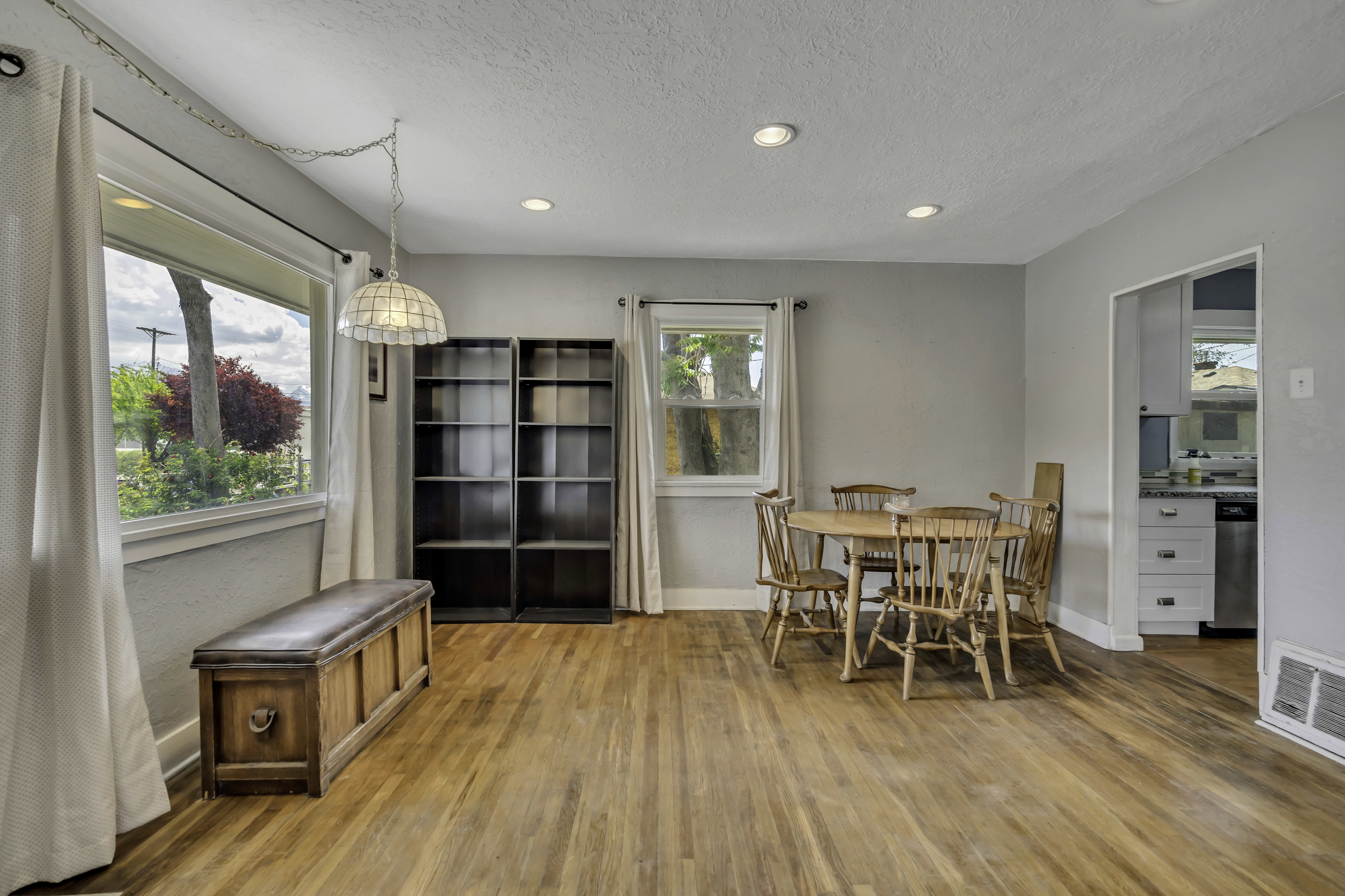 Light-filled living space featuring wood-finish flooring, recessed lighting, and a kitchen entry