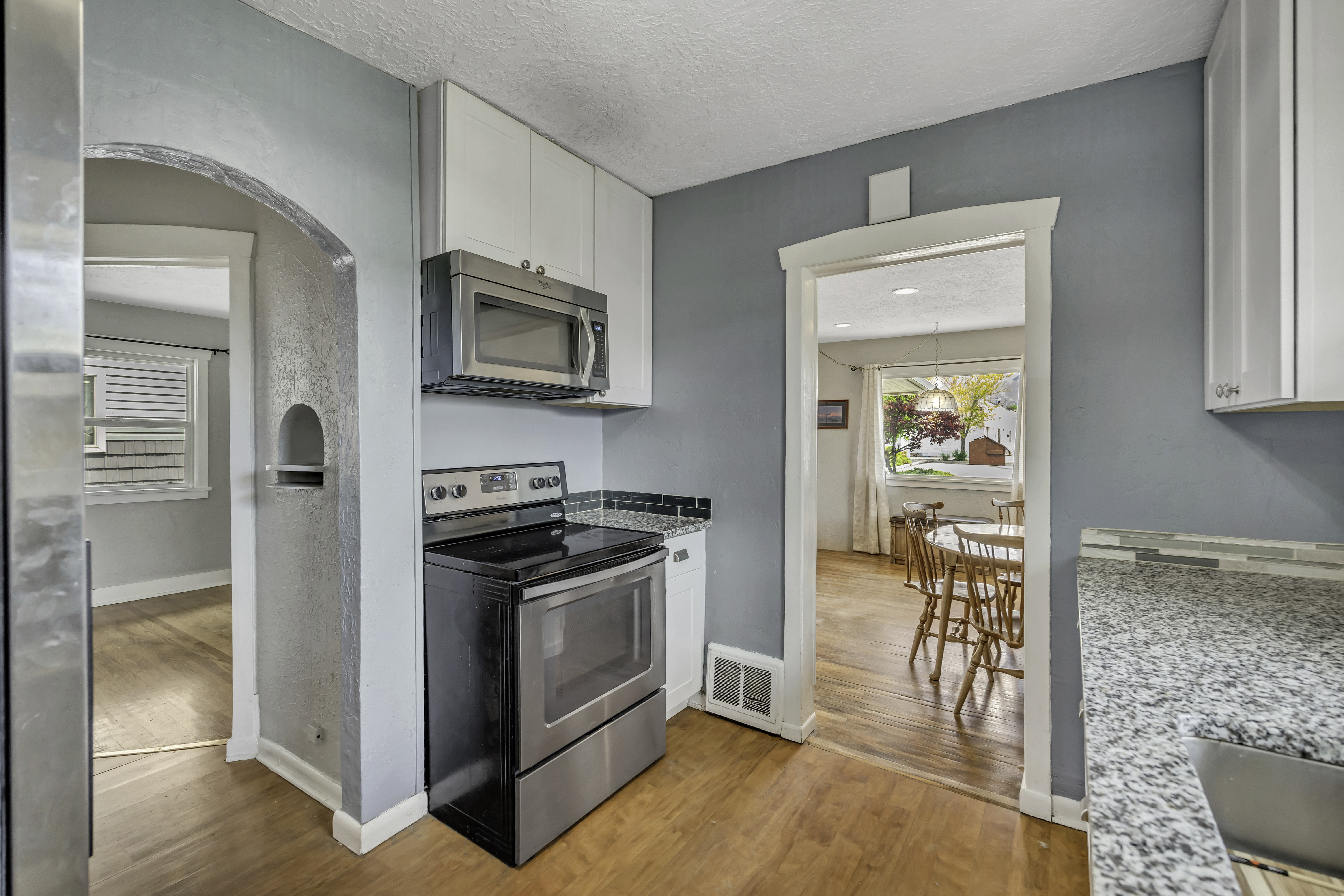 Kitchen featuring a stainless steel range, built-in microwave, white cabinetry, and granite-finish countertops
