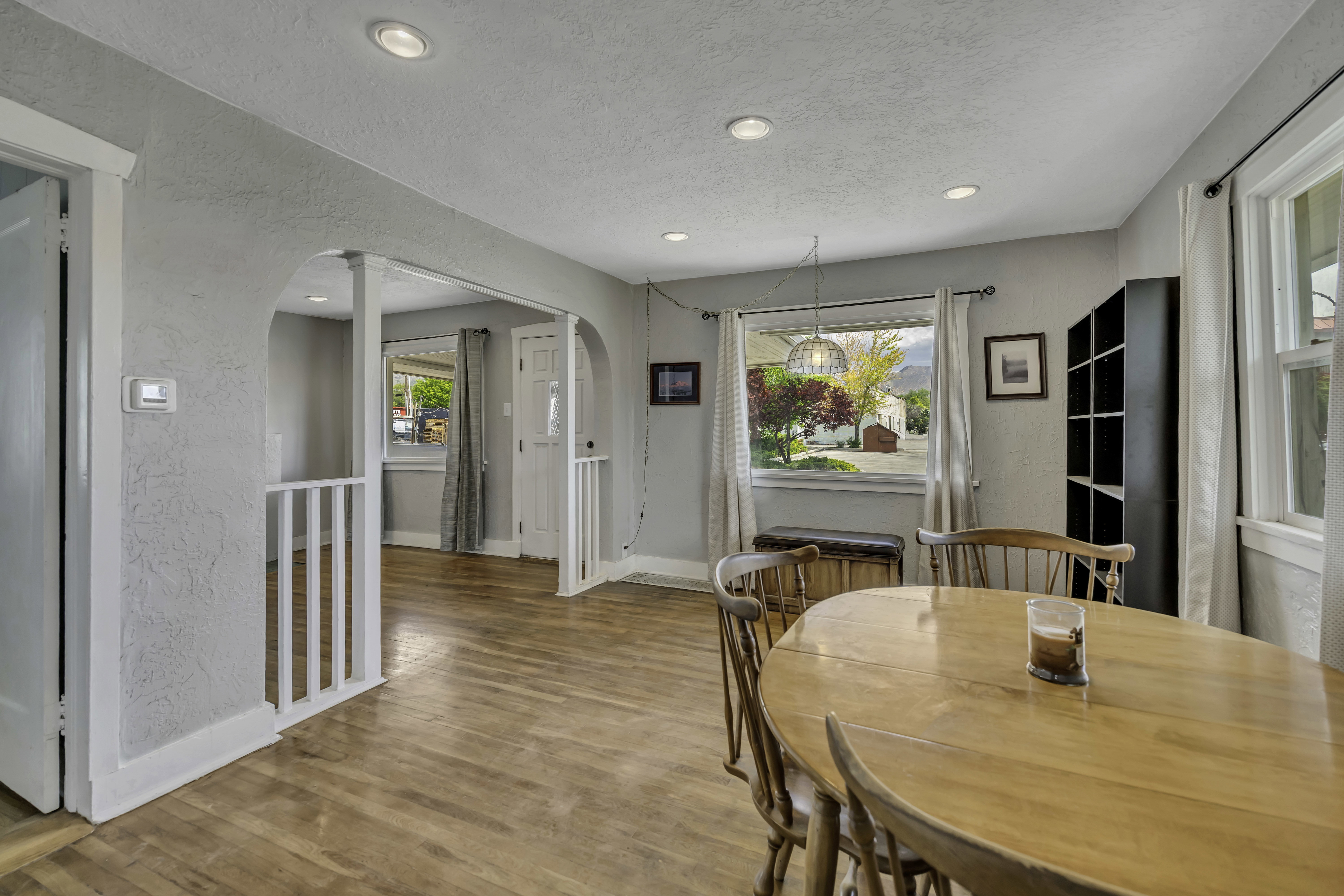 Open dining area featuring wood-finish flooring, recessed lighting, and an arched entry