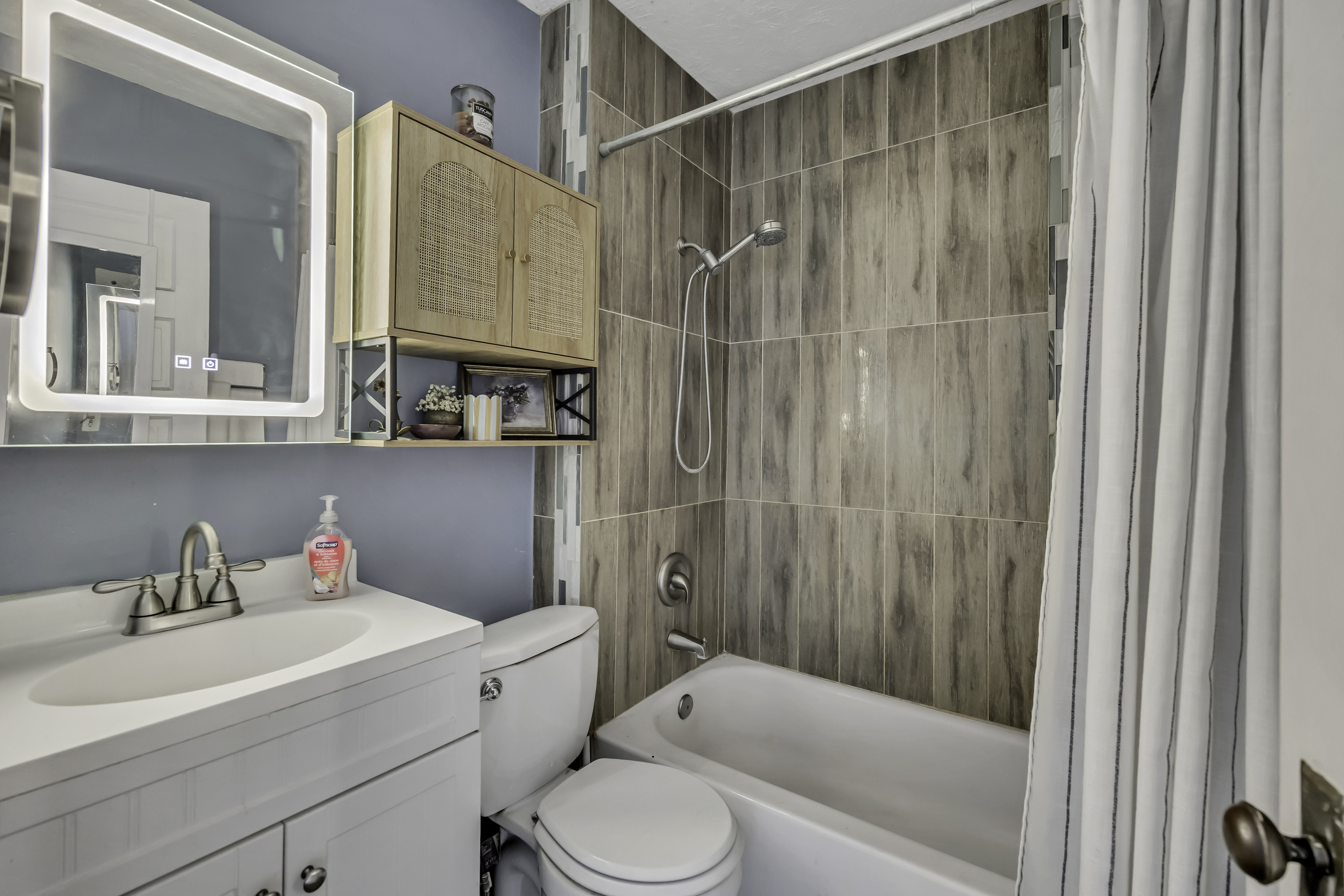 Bathroom featuring a white vanity with integrated sink, brushed nickel faucet, and an illuminated mirror