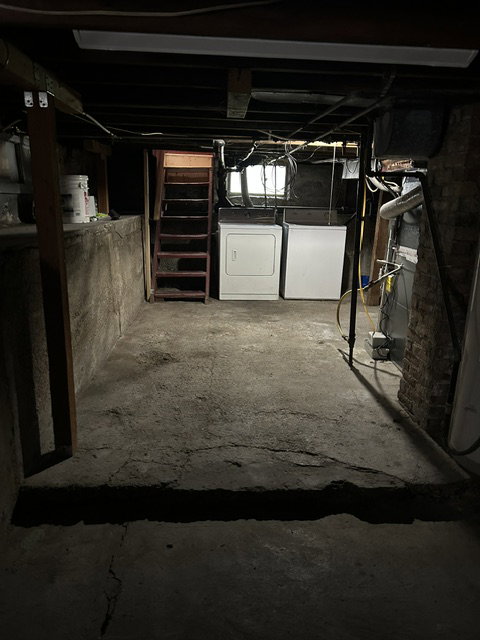 Basement laundry area featuring concrete flooring and exposed ceiling joists
