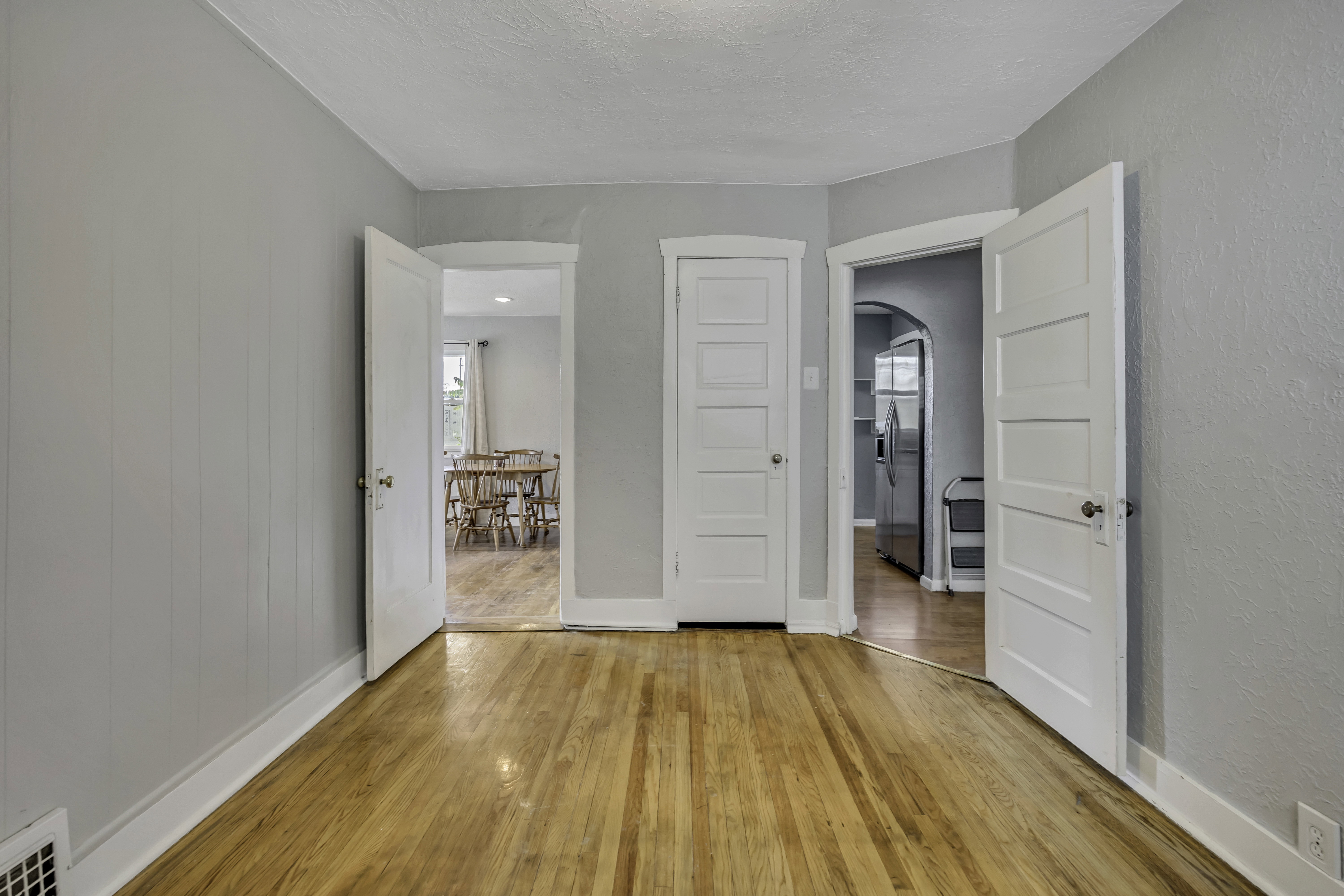 Hardwood flooring throughout, light gray wall paint, white trim, and paneled interior doors