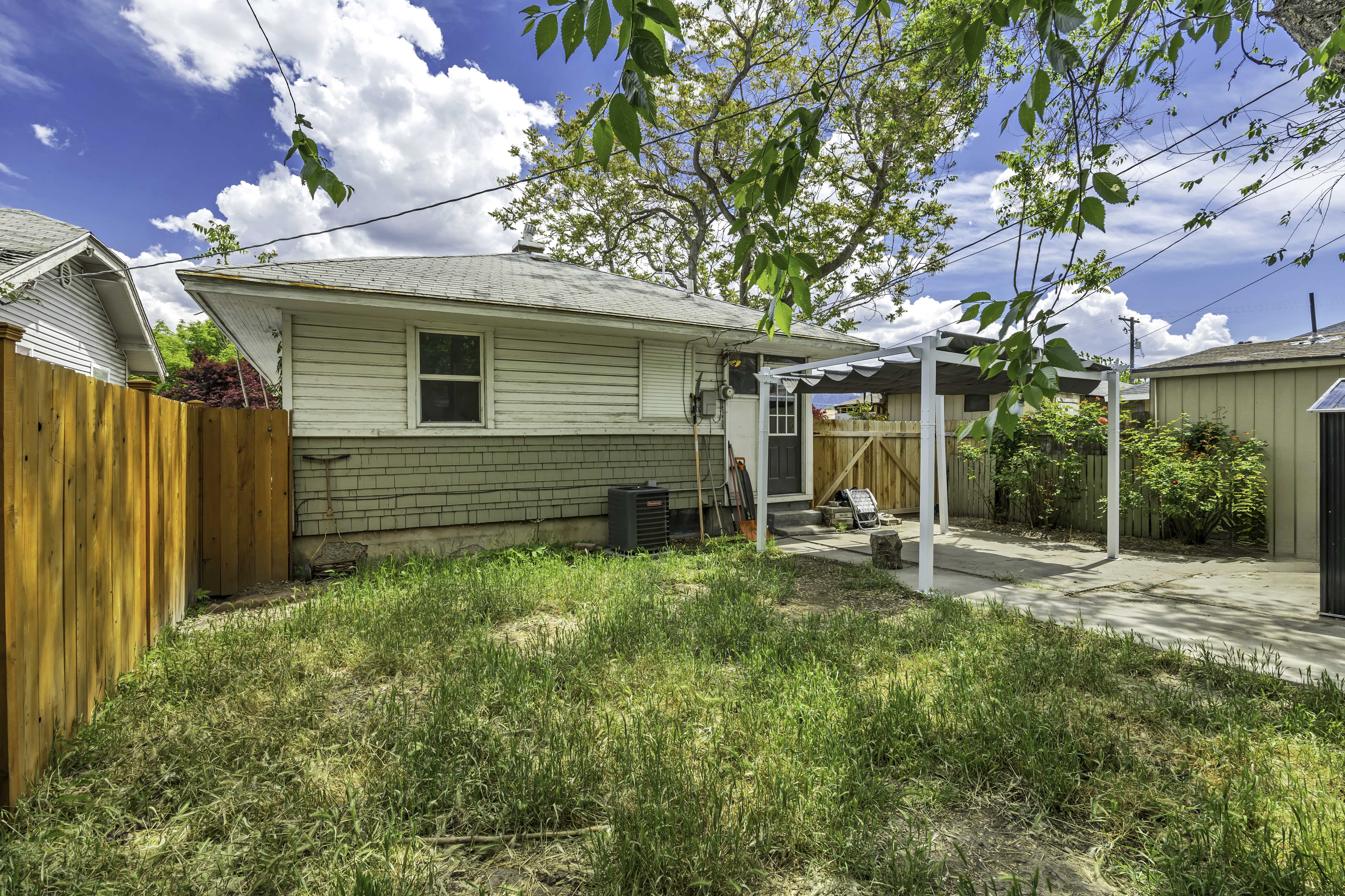 Backyard featuring a covered patio structure, partial wood fencing, and a concrete driveway